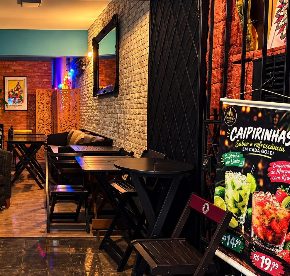 Salão interno do bar do 666 Pinheiros, com mesas e iluminação neon